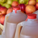 jugs of apple cider beside apples